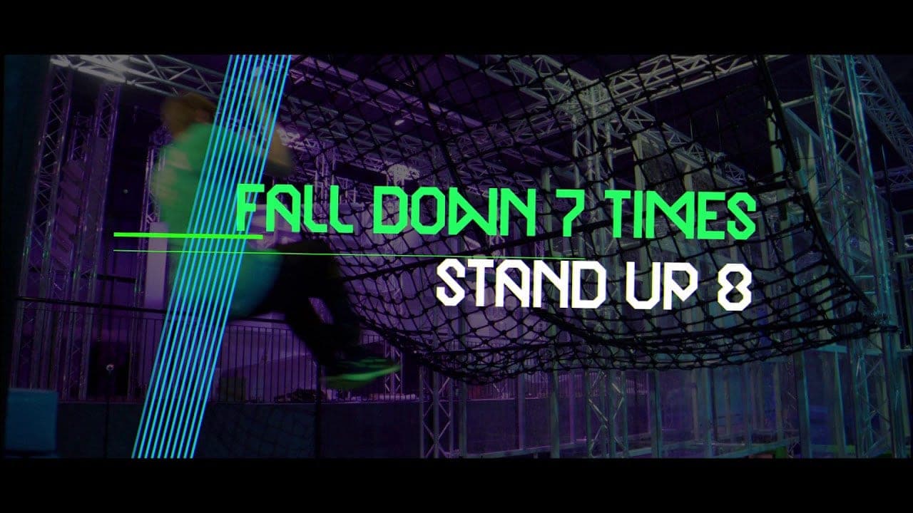 Jump Inc promo still: “Fall down 7 times, stand up 8” in neon over the trampoline park